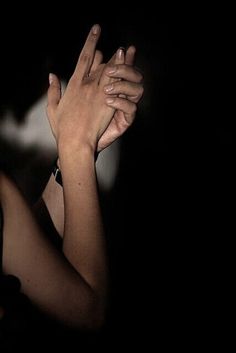 two people are holding their hands together in the dark, with one person's hand raised up