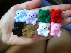 a person holding five small teddy bears in their hand, all different colors and sizes