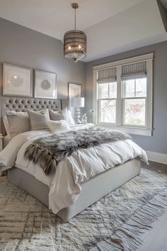 a large bed sitting in a bedroom next to two windows and a chandelier