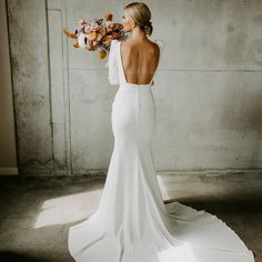 a woman in a white wedding dress holding a bunch of flowers and looking up at the sky