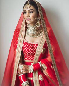 a woman in a red and gold bridal outfit with her hands on her hips