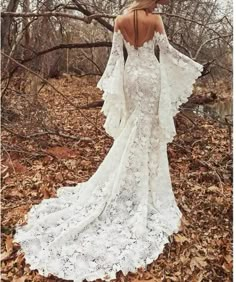 a woman in a white dress and hat is walking through the woods with her back to the camera