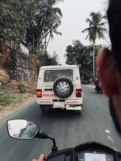 a police van driving down the road with palm trees in the backgrouds