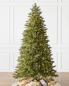 a small christmas tree in a bowl with gold bows on the bottom and presents under it