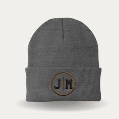 a grey beanie with the word j m on it and a brown circle in the middle