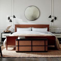 a bedroom with a bed, nightstands and mirror on the wall above it's headboard