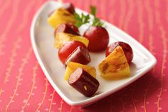 a white plate topped with fruit and veggies on top of a red table