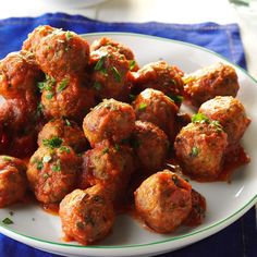 a white plate topped with meatballs covered in sauce and garnished with parsley