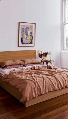 a large bed sitting next to a window on top of a hard wood floored floor