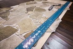 a ruler is laying on top of a wooden table with stone tiles and wood flooring