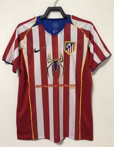 a red and white striped soccer jersey hanging on a hanger with a spider logo