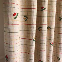 a curtain with red flowers on it in front of a white wall and window sill