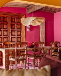 a dining room with pink walls and wooden furniture