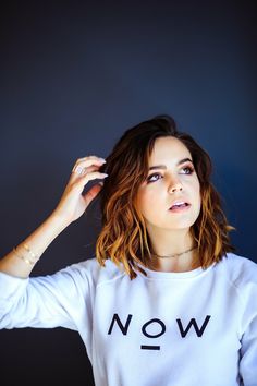 a woman in a white sweatshirt with the word now printed on it's chest