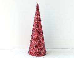 a red glittered cone shaped tree on a white surface with the top half turned upside down