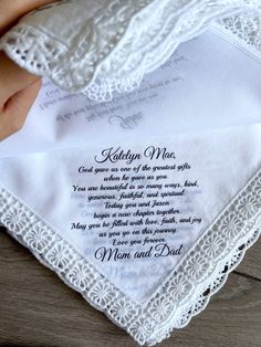 a white handkerchief with an embroidered poem on it and a hand holding the hanket