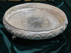 a silver plate sitting on top of a green cloth