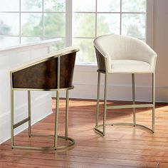 two chairs sitting next to each other on a hard wood floor in front of a window