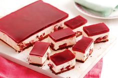 several pieces of dessert sitting on top of a white cutting board next to a pink napkin