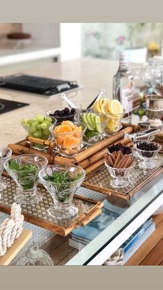 an assortment of food on trays sitting on a kitchen counter with bottles and glasses