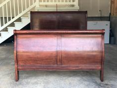 a wooden bed frame sitting next to a stair case