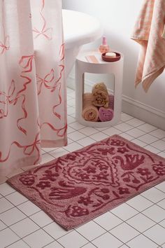 a bathroom with pink rugs and towels on the floor