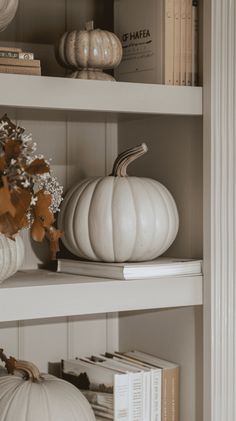 some white pumpkins are sitting on shelves in a room with books and other decorations