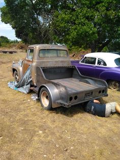 an old pick up truck sitting in the middle of a field next to other cars