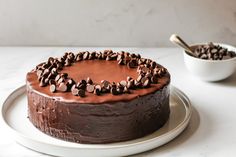 a chocolate cake sitting on top of a white plate next to a bowl of chocolate chips