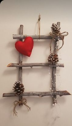 a red heart is hanging on a wooden frame made out of branches and pine cones