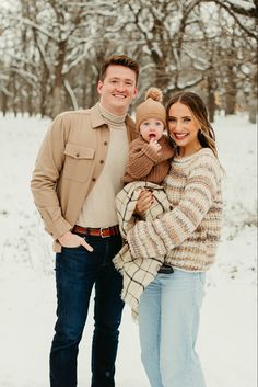 a man and woman holding a baby in the snow