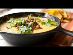 a black skillet filled with food on top of a wooden table next to chips