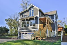 a two story house with stairs leading up to the front door and second story above it