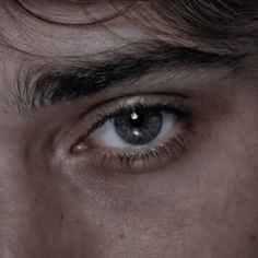 a man's eye is shown in this close up photo, with dark hair