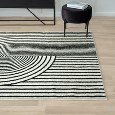 a black and white area rug with an abstract design on the floor next to a chair