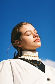 a woman with her eyes closed wearing a white shirt