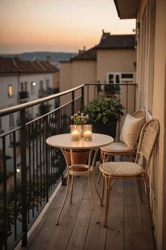 two wicker chairs and table on a balcony with candles in front of the railing