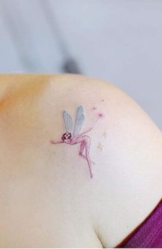 a small tattoo on the back of a woman's left shoulder, depicting a pink fairy