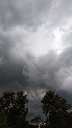 the sky is filled with dark clouds and trees