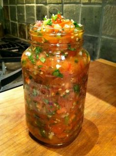 a jar filled with lots of food sitting on top of a wooden table next to a stove