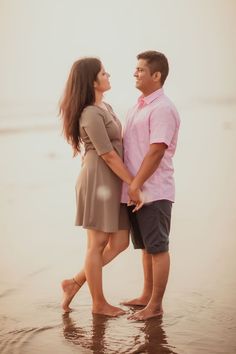 a man and woman are standing in the water at the beach holding each other's hands