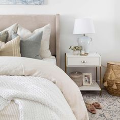 a bedroom with white walls and neutral bedding