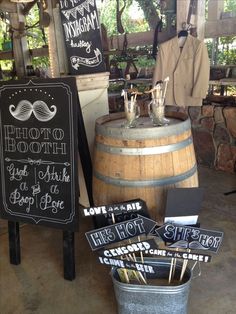 some signs are sitting on top of a barrel in front of a sign that says, photo booth