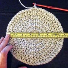 someone is measuring the size of a crochet dishcloth with a tape measure