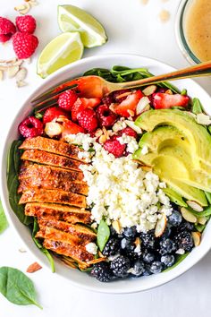 a bowl filled with chicken, berries and avocado