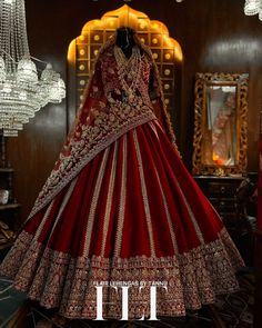 a red and gold wedding gown on display in a room with chandelier hanging from the ceiling