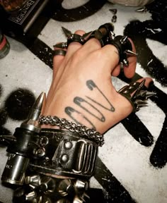 a person with tattoos on their arm holding onto some metal bracelets and scissors in the other hand