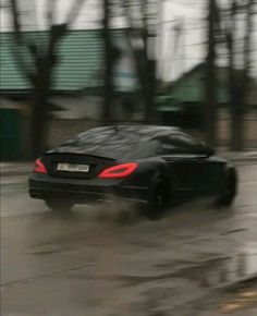 a black sports car driving down a street in the rain