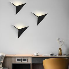 three black triangles hanging on the wall above a desk