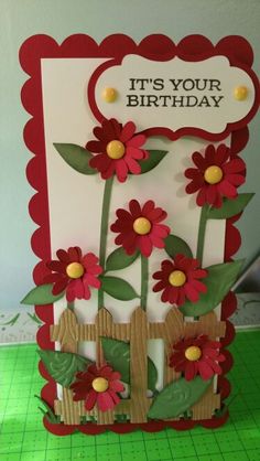 a card with red flowers and a wooden fence